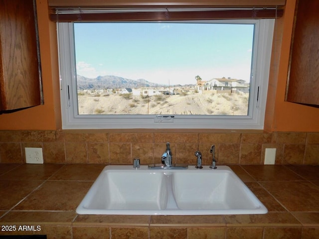 room details with tile countertops, a mountain view, and a sink