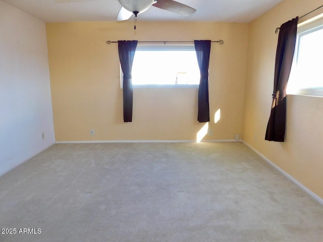 unfurnished room with baseboards, plenty of natural light, a ceiling fan, and light colored carpet