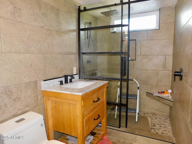 bathroom with toilet, a stall shower, tile walls, and vanity