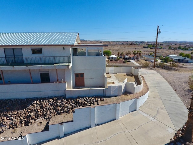 exterior space with metal roof, a balcony, and stucco siding