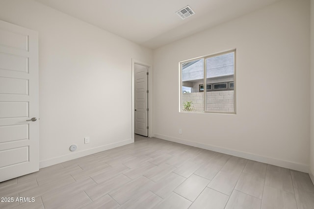 spare room with baseboards, visible vents, and wood finish floors