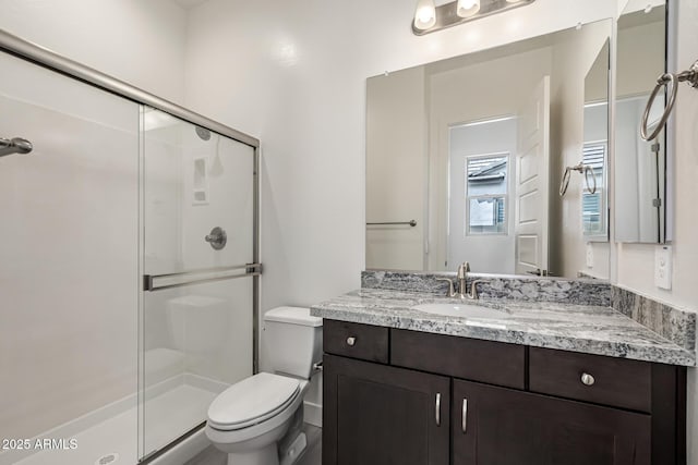 full bath with a stall shower, toilet, and vanity