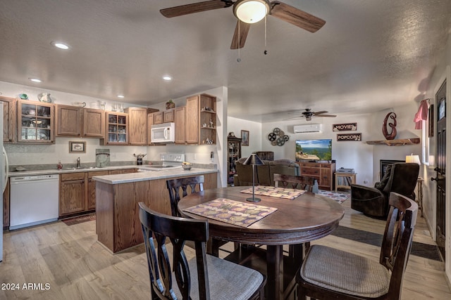 dining room featuring sink, ceiling fan, a textured ceiling, and light wood-type flooring