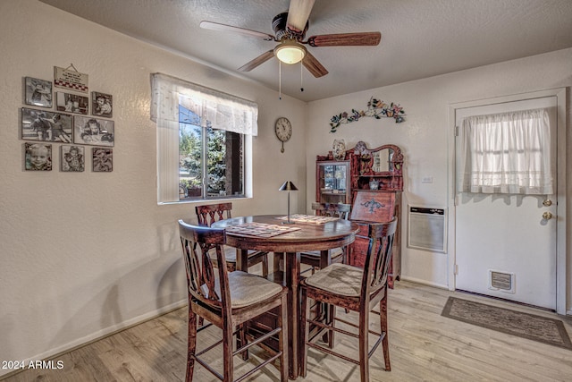 dining room with ceiling fan, heating unit, a textured ceiling, and light wood-type flooring