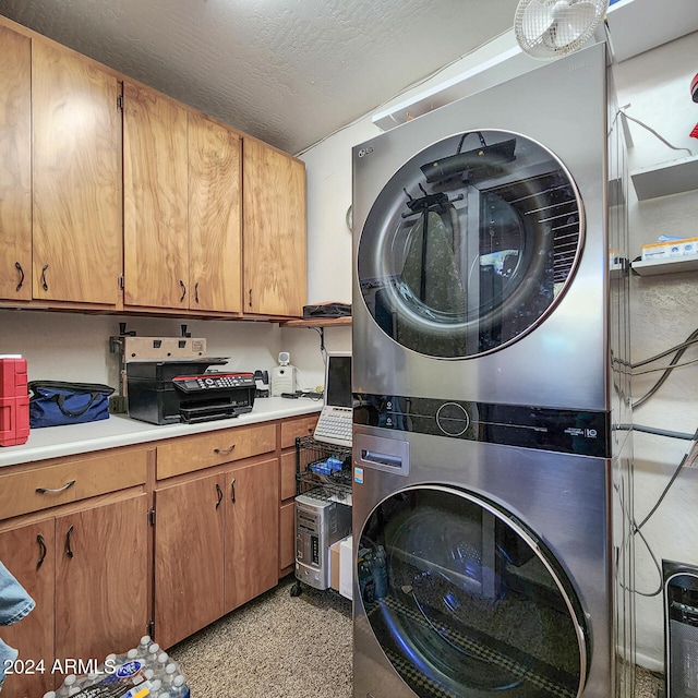 laundry room featuring stacked washer / dryer and a textured ceiling