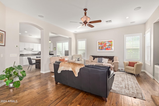 living room featuring dark wood-type flooring, a healthy amount of sunlight, and ceiling fan