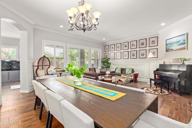 dining area with an inviting chandelier, crown molding, and dark hardwood / wood-style flooring