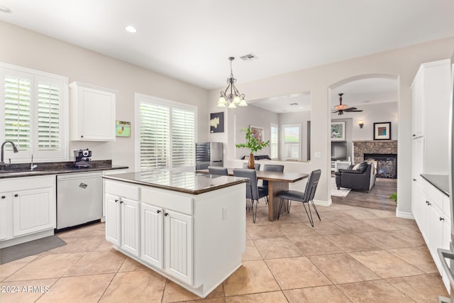 kitchen featuring white cabinetry, a wealth of natural light, stainless steel dishwasher, and ceiling fan with notable chandelier