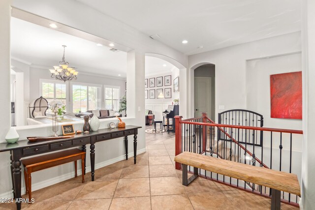 hallway with crown molding, light tile patterned flooring, and a notable chandelier