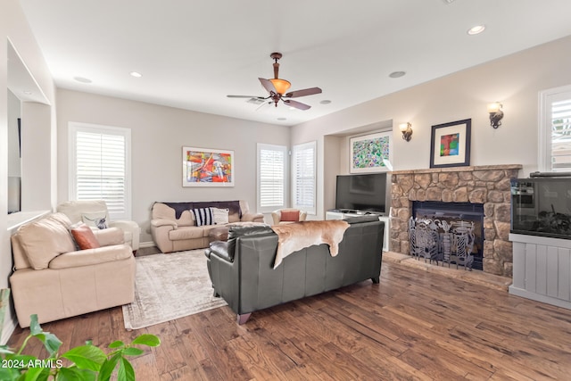 living room with dark wood-type flooring, a fireplace, a healthy amount of sunlight, and ceiling fan