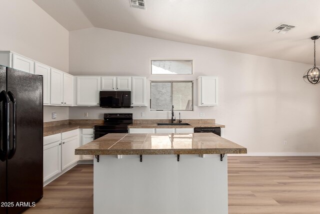 30212 N Sunray Dr, San Tan Valley, AZ 85143 - kitchen featuring black appliances, tile counters, a sink, a breakfast bar area, and light wood-style floors