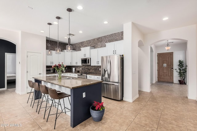 kitchen featuring a center island, dark stone counters, decorative light fixtures, white cabinets, and appliances with stainless steel finishes