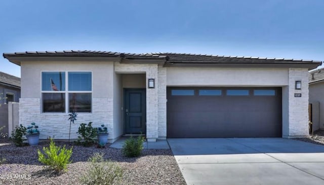 prairie-style home featuring stucco siding, an attached garage, stone siding, and concrete driveway