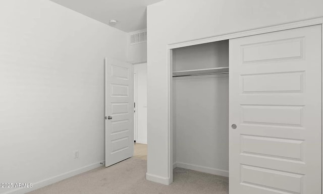 unfurnished bedroom with a closet, baseboards, light carpet, and visible vents