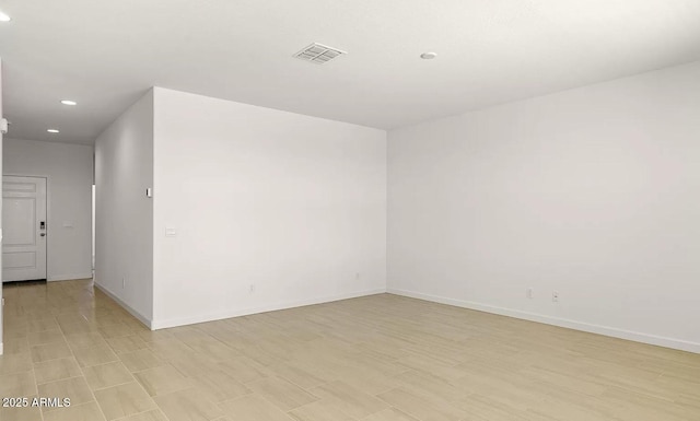 empty room featuring baseboards, visible vents, and recessed lighting