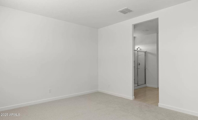 empty room with light colored carpet, baseboards, and visible vents
