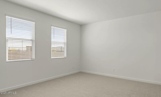 empty room featuring light colored carpet and baseboards
