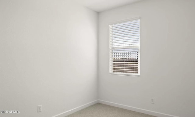 spare room featuring light colored carpet and baseboards