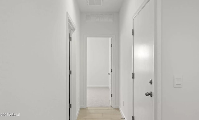 hallway with visible vents, baseboards, and light tile patterned floors