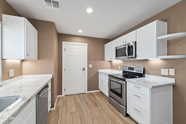 kitchen with appliances with stainless steel finishes, visible vents, white cabinetry, and open shelves