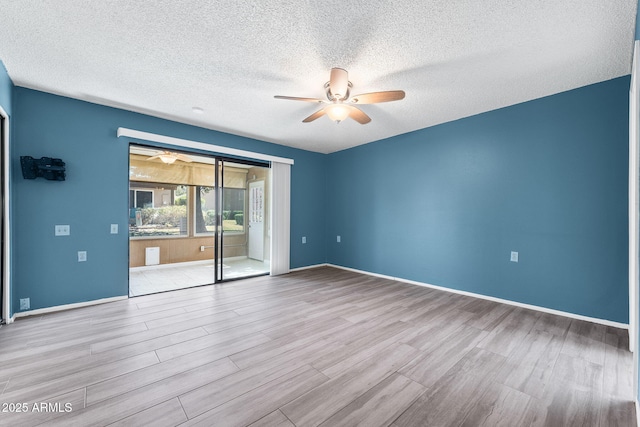 empty room with ceiling fan, a textured ceiling, baseboards, and wood finished floors