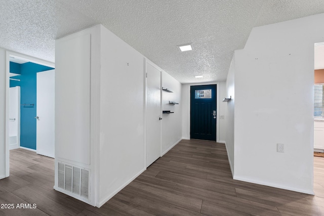 foyer with a textured ceiling, wood finish floors, visible vents, and baseboards