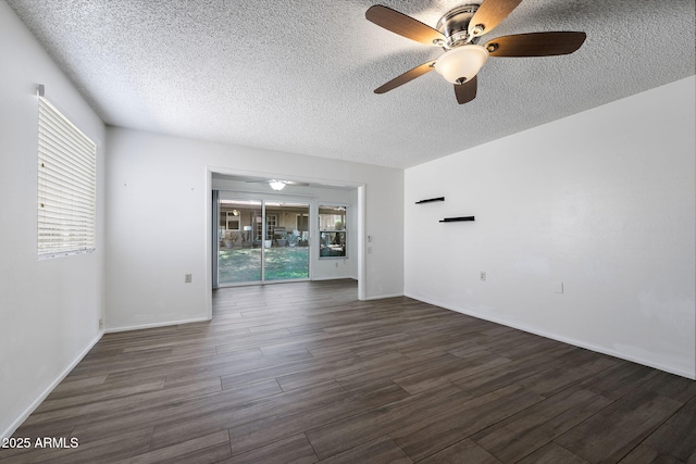 spare room with dark wood-style flooring, plenty of natural light, a textured ceiling, and baseboards