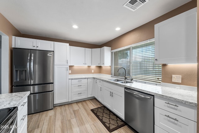 kitchen with light wood finished floors, white cabinetry, appliances with stainless steel finishes, and a sink