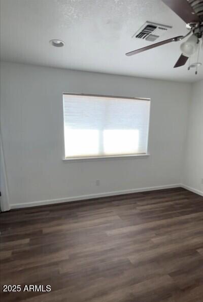 spare room with healthy amount of natural light, a ceiling fan, dark wood finished floors, and baseboards