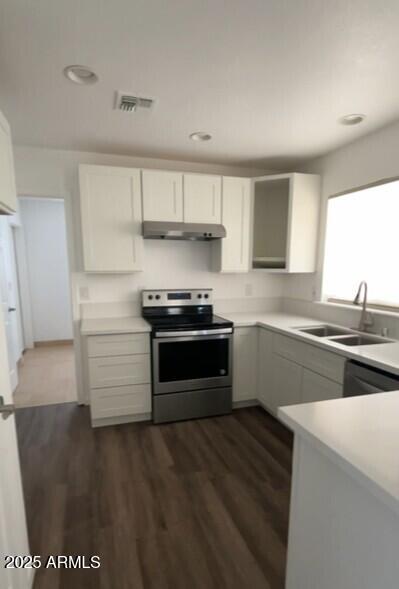 kitchen featuring stainless steel electric stove, a sink, under cabinet range hood, light countertops, and recessed lighting