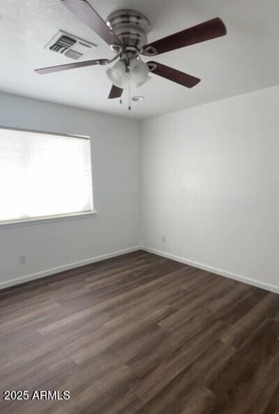 spare room with ceiling fan, dark wood-style flooring, and baseboards