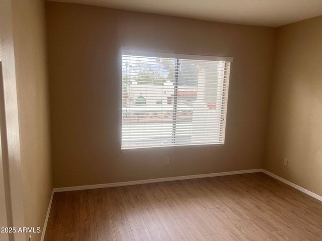 unfurnished room with baseboards and wood finished floors