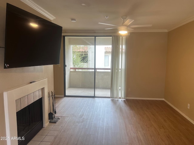 unfurnished living room featuring a ceiling fan, baseboards, a fireplace, ornamental molding, and light wood-style floors