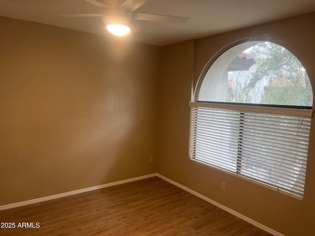 unfurnished room with baseboards, wood finished floors, and a ceiling fan