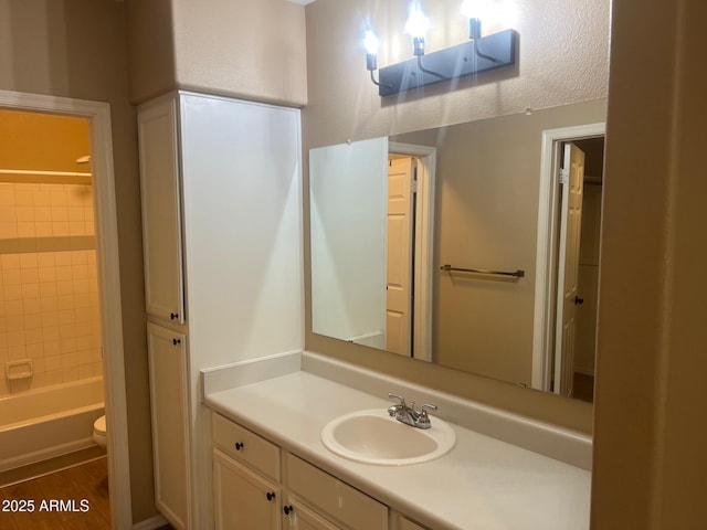 bathroom with vanity, toilet, wood finished floors, and shower / washtub combination