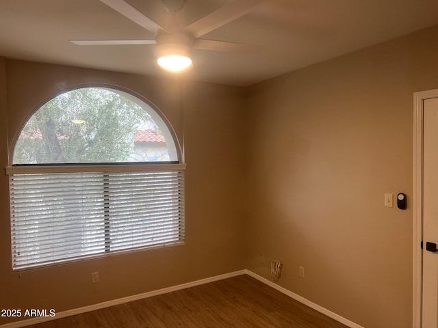 empty room featuring wood finished floors, baseboards, and ceiling fan