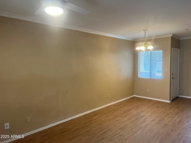 unfurnished room featuring an inviting chandelier, crown molding, wood finished floors, and baseboards