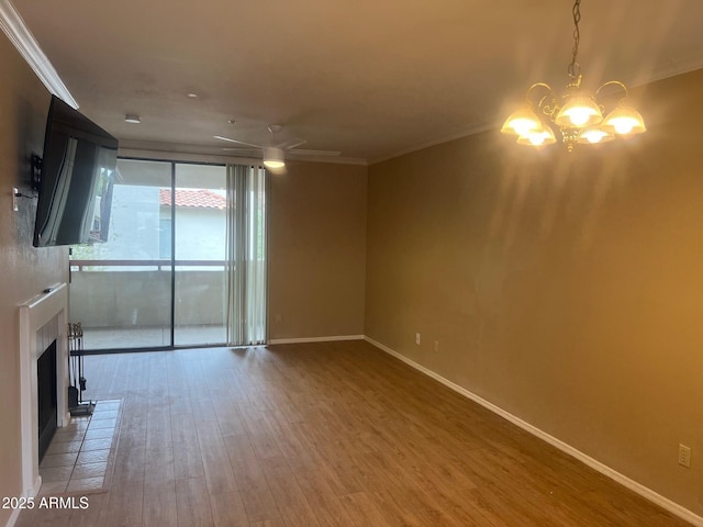 unfurnished living room with wood finished floors, baseboards, a fireplace, crown molding, and ceiling fan with notable chandelier