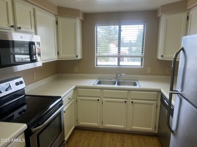 kitchen featuring light wood-style flooring, a sink, stainless steel appliances, light countertops, and white cabinets