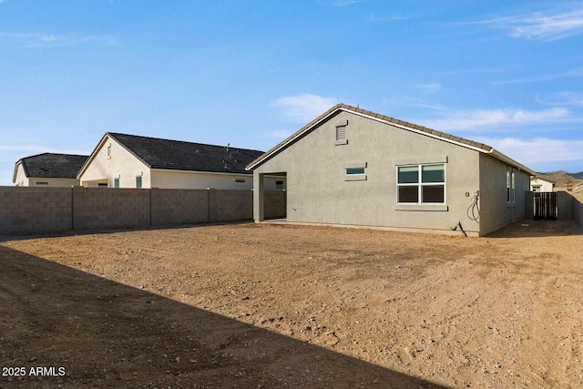 back of property with a fenced backyard and stucco siding