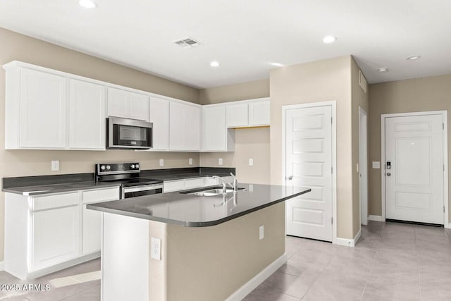 kitchen featuring visible vents, dark countertops, a sink, light tile patterned floors, and stainless steel appliances