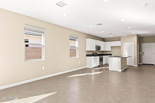 kitchen featuring dark countertops, baseboards, open floor plan, recessed lighting, and appliances with stainless steel finishes
