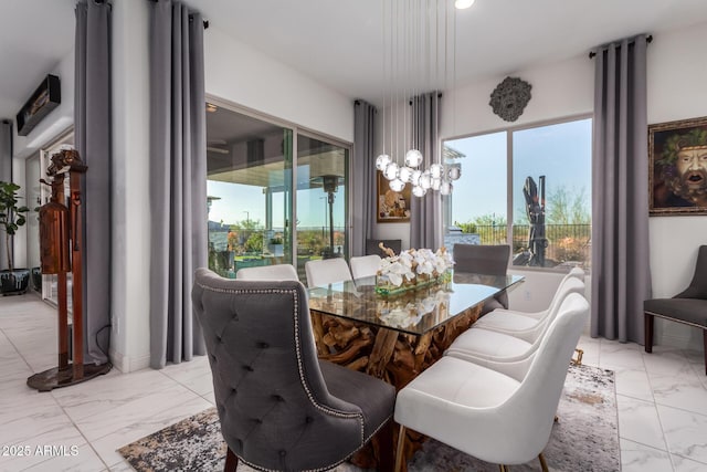 dining area with marble finish floor, a wealth of natural light, and an inviting chandelier