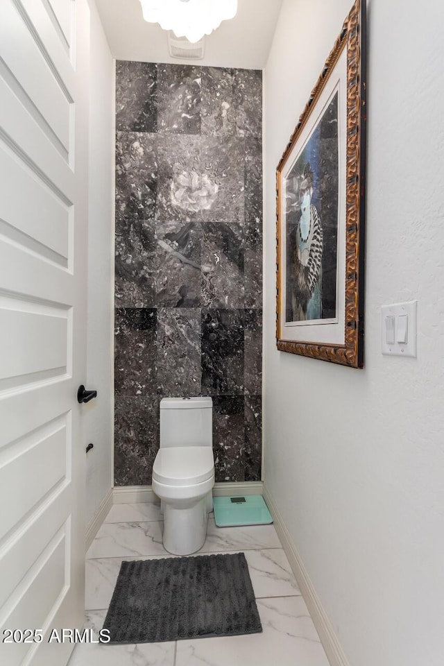 bathroom with marble finish floor, toilet, and baseboards