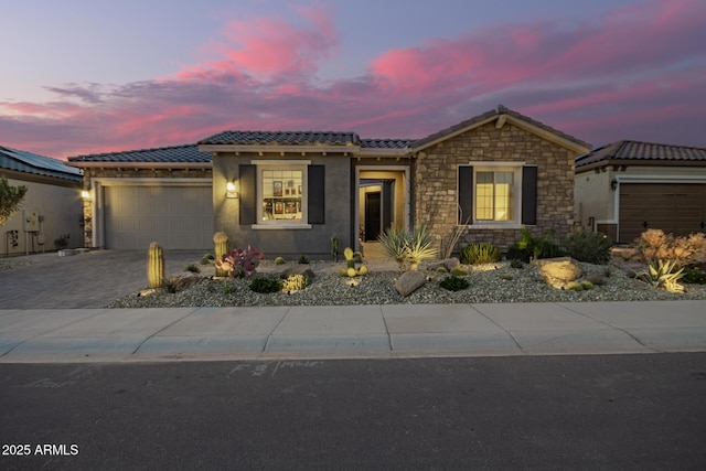 view of front of home with a garage, decorative driveway, a tile roof, and stucco siding