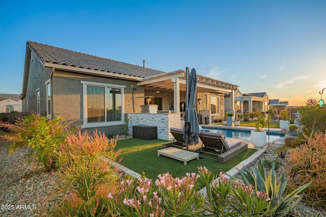 back of house featuring fence, a tile roof, a fenced in pool, a pergola, and stucco siding