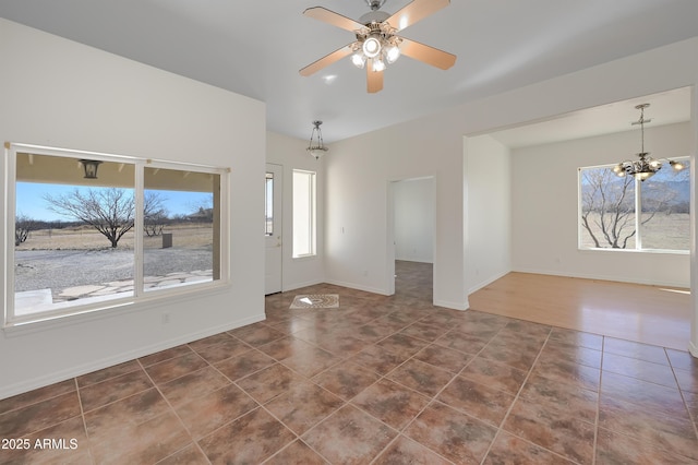 interior space featuring ceiling fan with notable chandelier and dark tile patterned floors