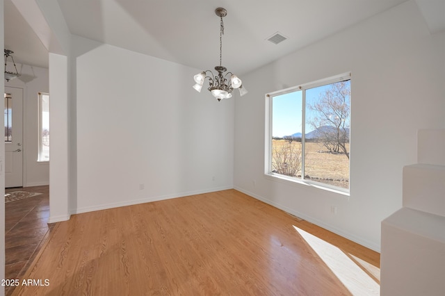 spare room featuring hardwood / wood-style flooring and a notable chandelier