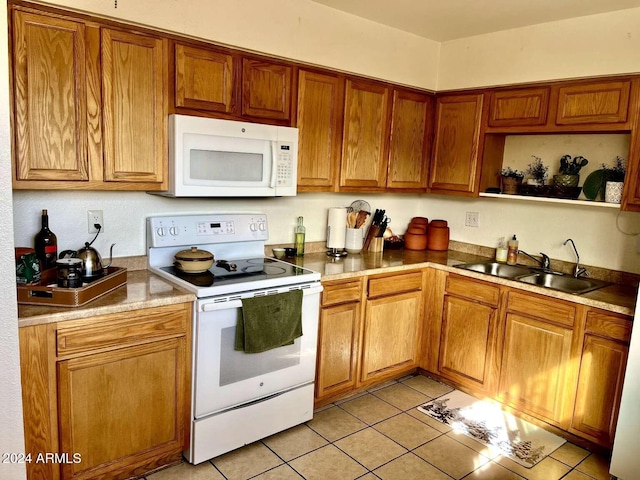 kitchen featuring white appliances, sink, and light tile patterned floors