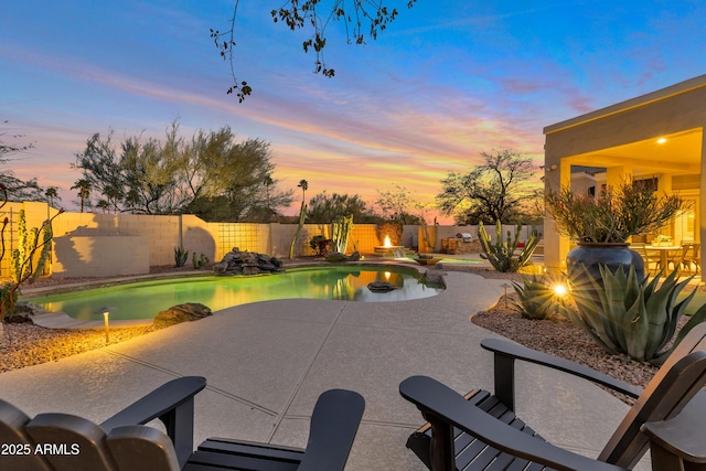 pool at dusk featuring a fenced in pool, a fenced backyard, and a patio